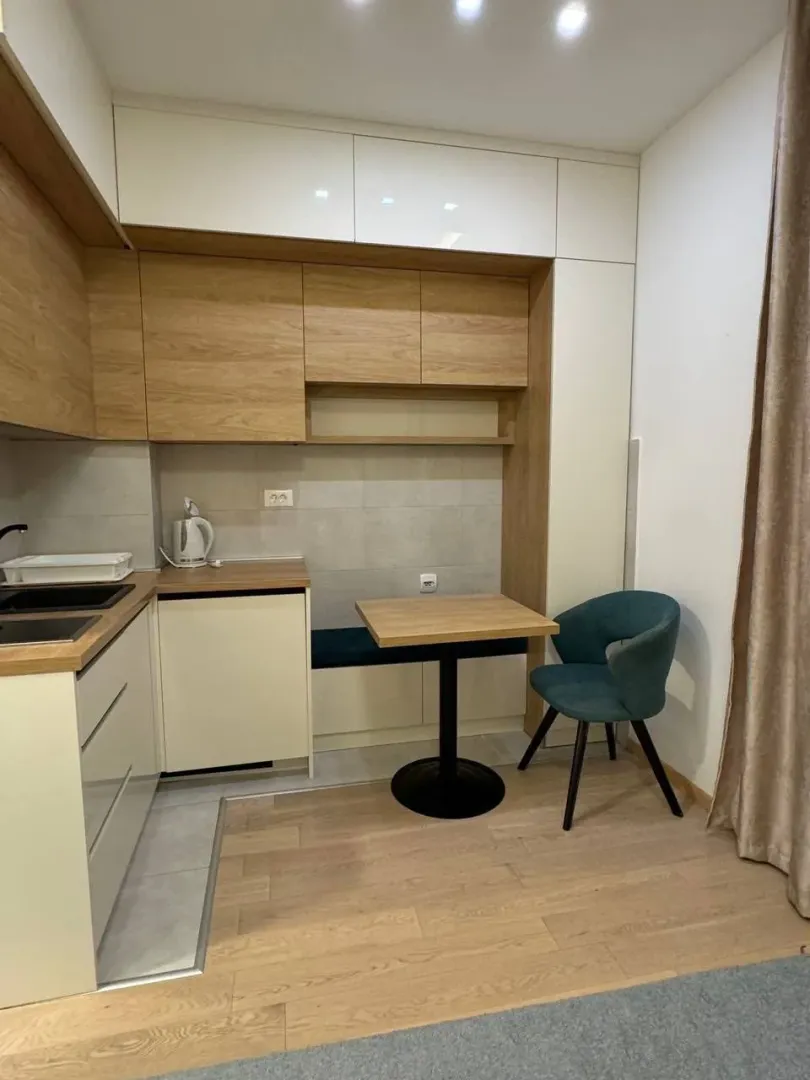 Small modern kitchen with wooden elements and a built-in dining table.