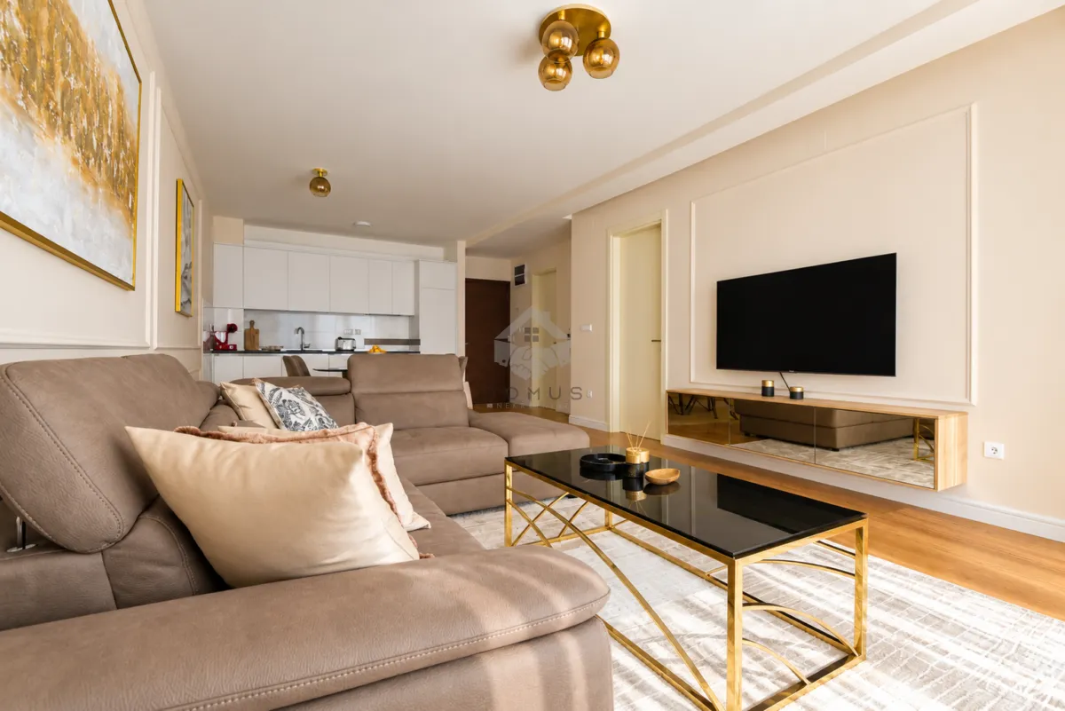 Spacious living room with a sofa, coffee table, and TV, connected to the kitchen.