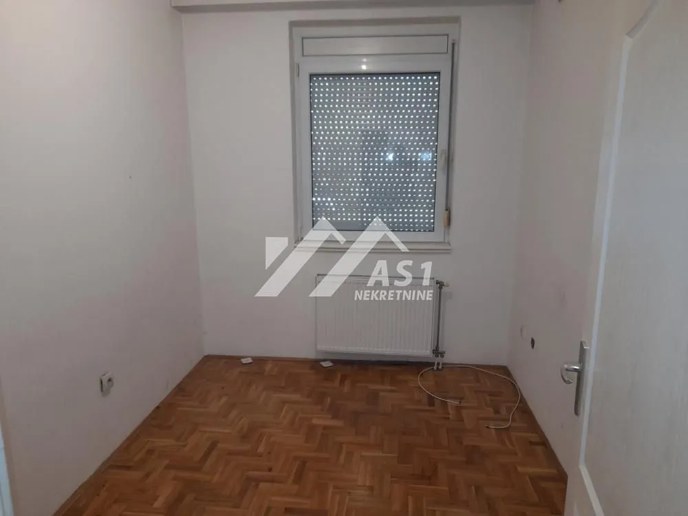 Empty room with parquet flooring and a window.