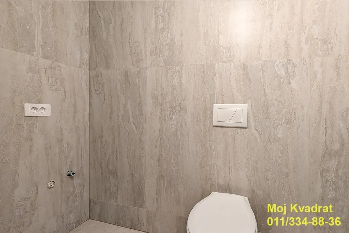 Kupatilo obloženo keramičkim pločicama sa ugradnim monoblokom.