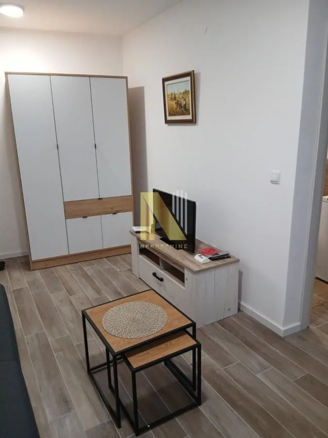 Dnevna soba sa ormanom, TV komodom i stočićem.