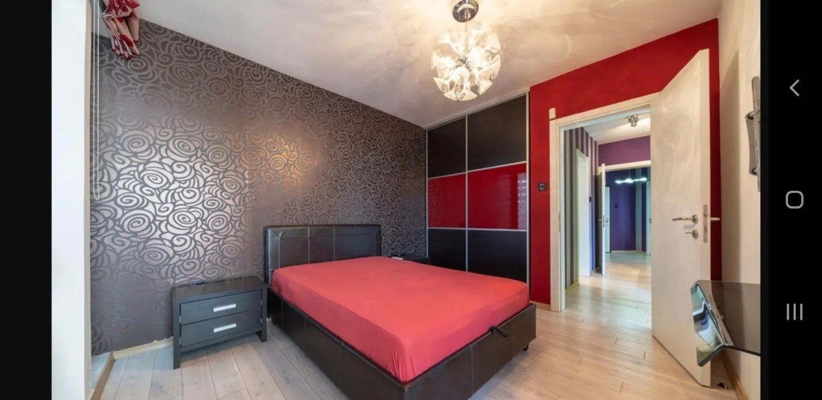 Svijetla spavaća soba sa modernim tapetama, crvenim krevetom i ugradnim plakarem.