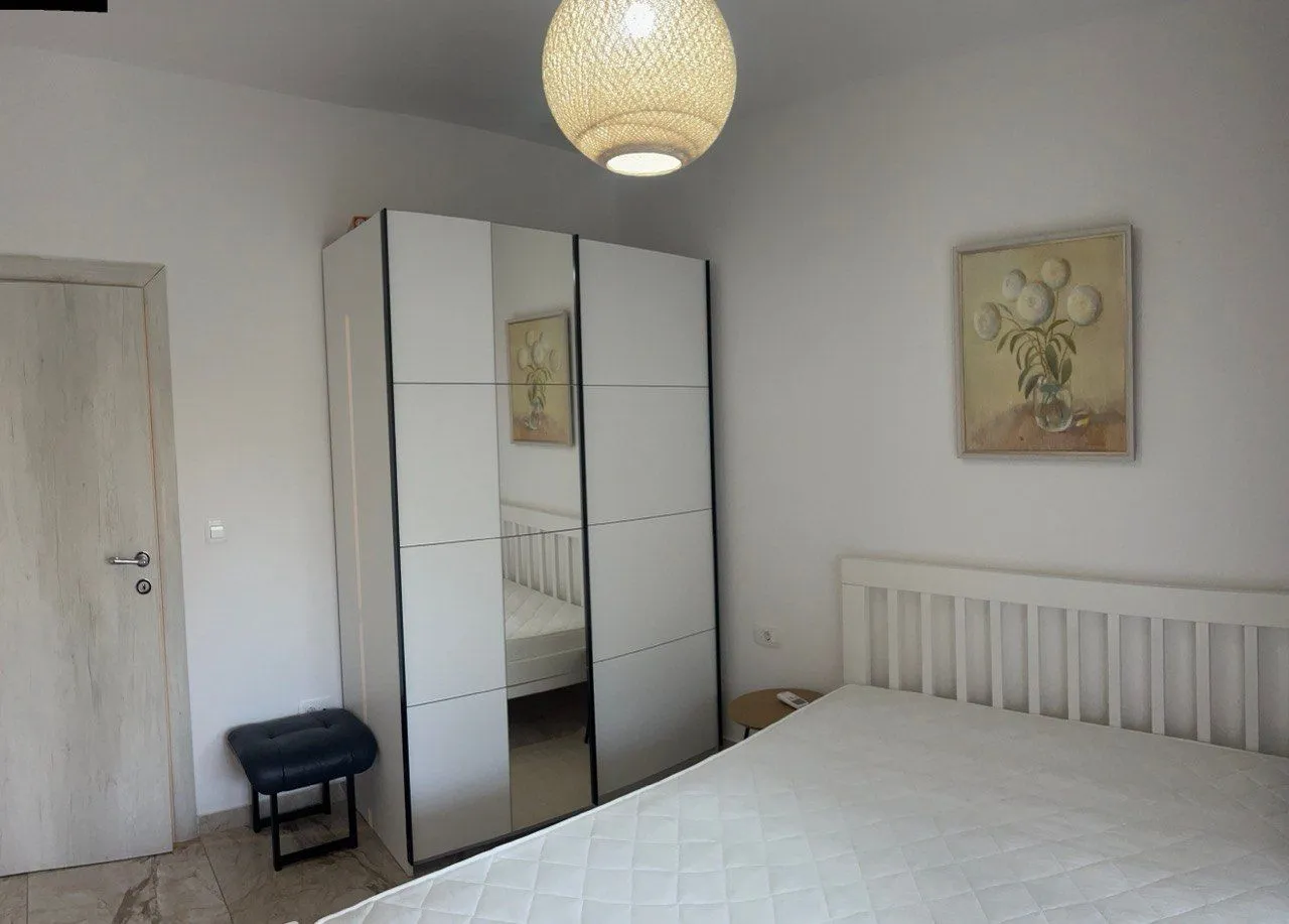 Furnished bedroom with a bed, wardrobe, and a painting on the wall.