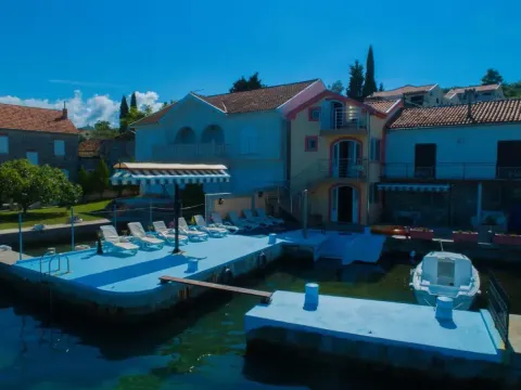 Pogled na privatnu obalu sa pontom, ležaljkama i privezanim čamcem ispred kuće. - image 5