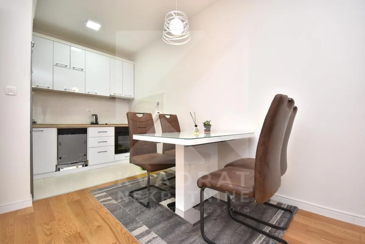 Small kitchen with white cabinets and a dining table with chairs.