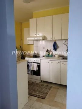 Pogled iz prolaza na manju kuhinju sa belim elementima i štednjakom. - image 12