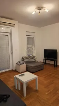 Manja dnevna soba sa kaučem, televizorom i parketom na podu. - image 6