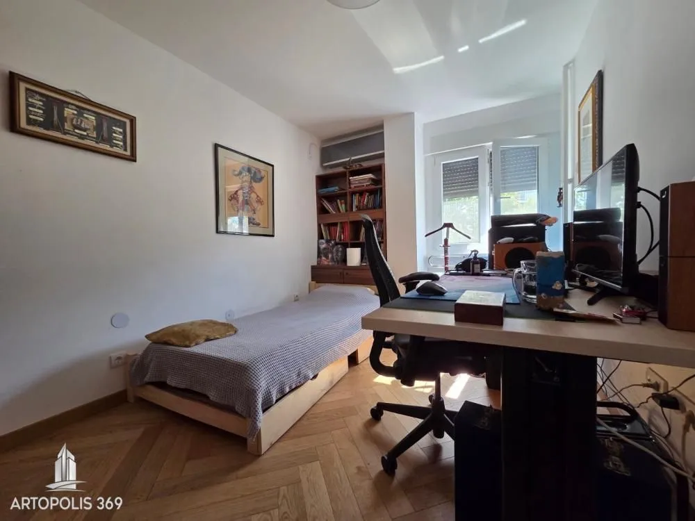 Manja spavaća soba sa krevetom, radnim stolom i policama za knjige.