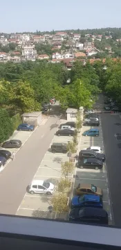 Pogled sa prozora na parking i zeleno naselje u daljini. - image 12