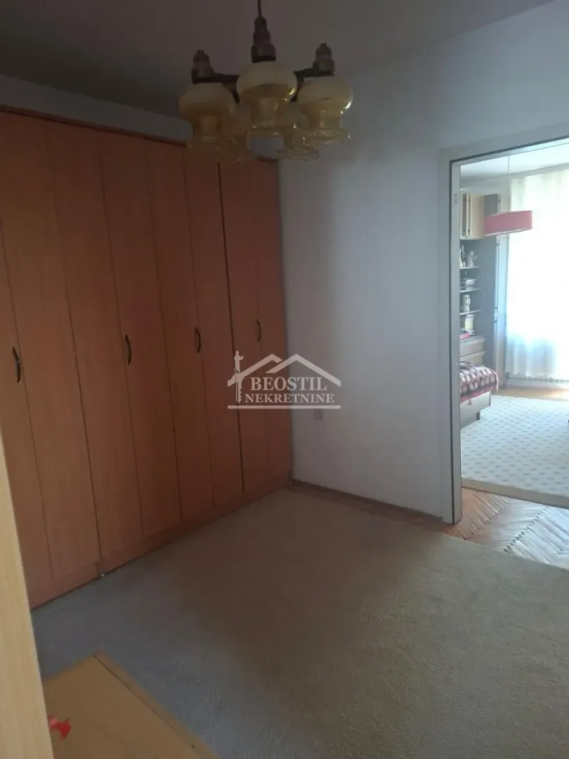 Spavaća soba sa velikim drvenim ormanom i lusterom.