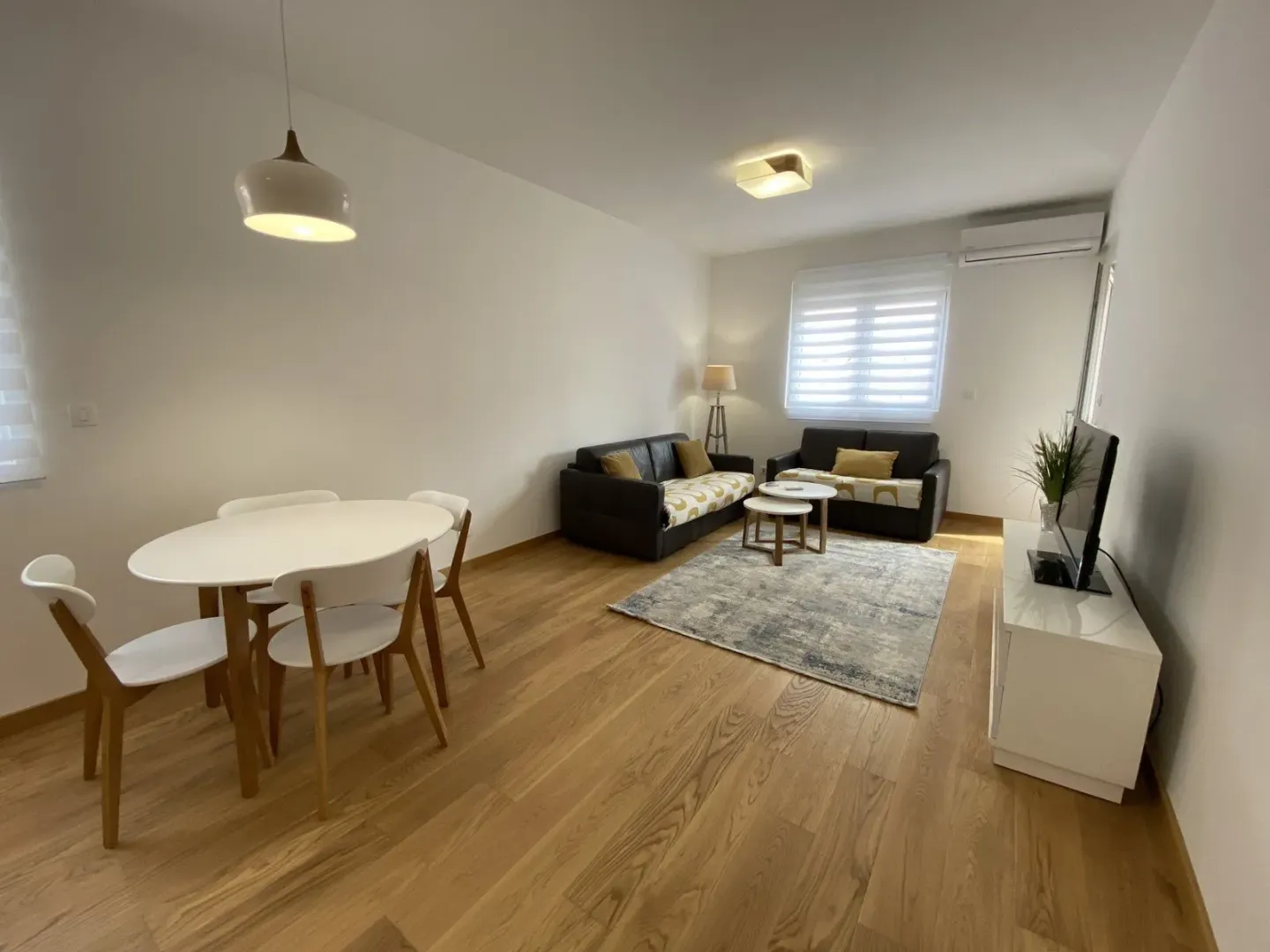 Svijetla dnevna soba sa trpezarijskim stolom i modernim namještajem.