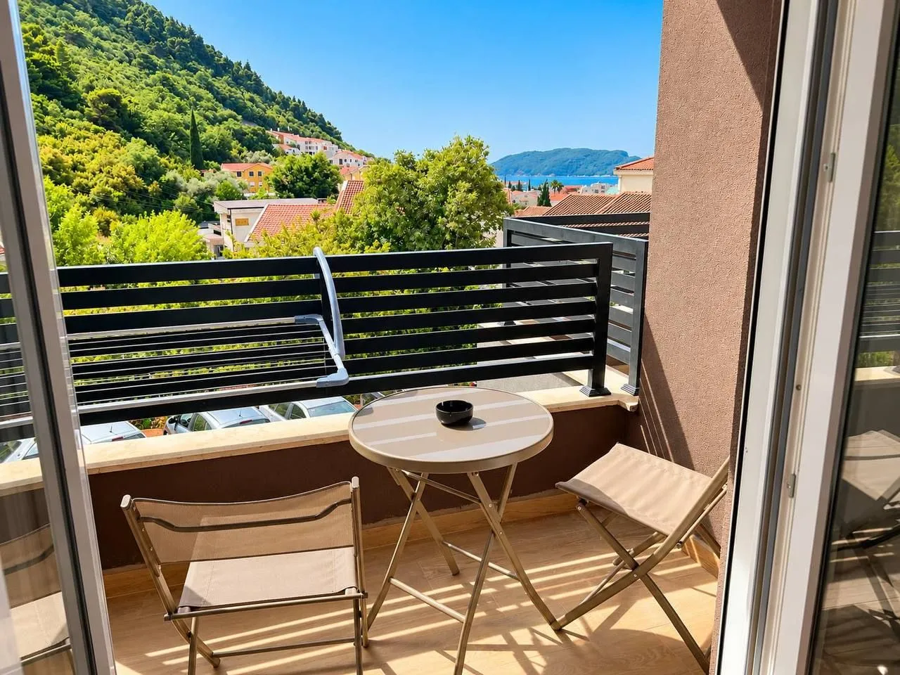Furnished balcony with seating set and view of greenery and the sea.