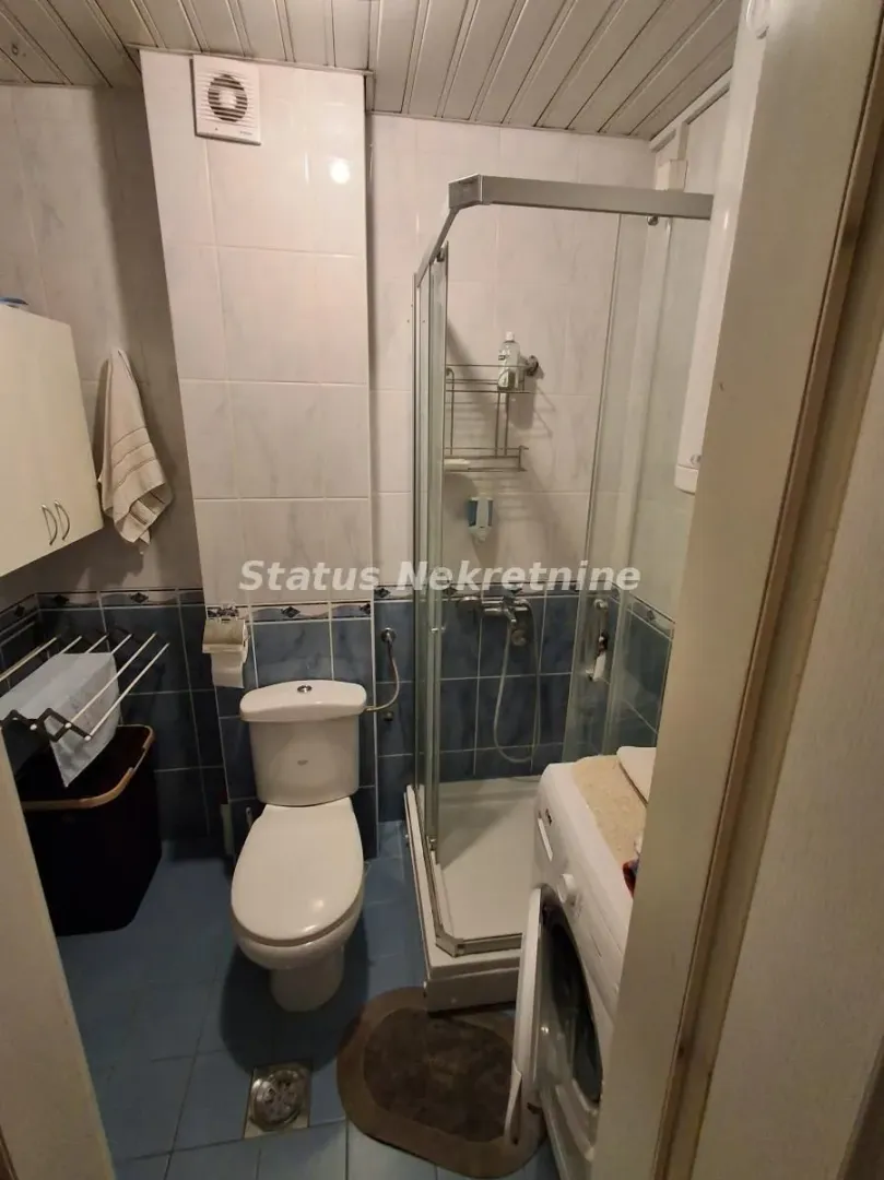 Manje kupatilo sa tuš kabinom, WC šoljom i veš mašinom.