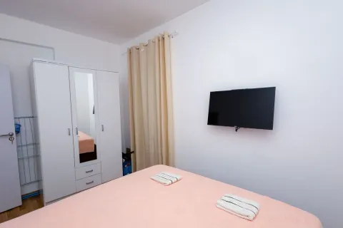 Namještena spavaća soba sa bračnim krevetom, garderoberom i televizorom na zidu. - image 3