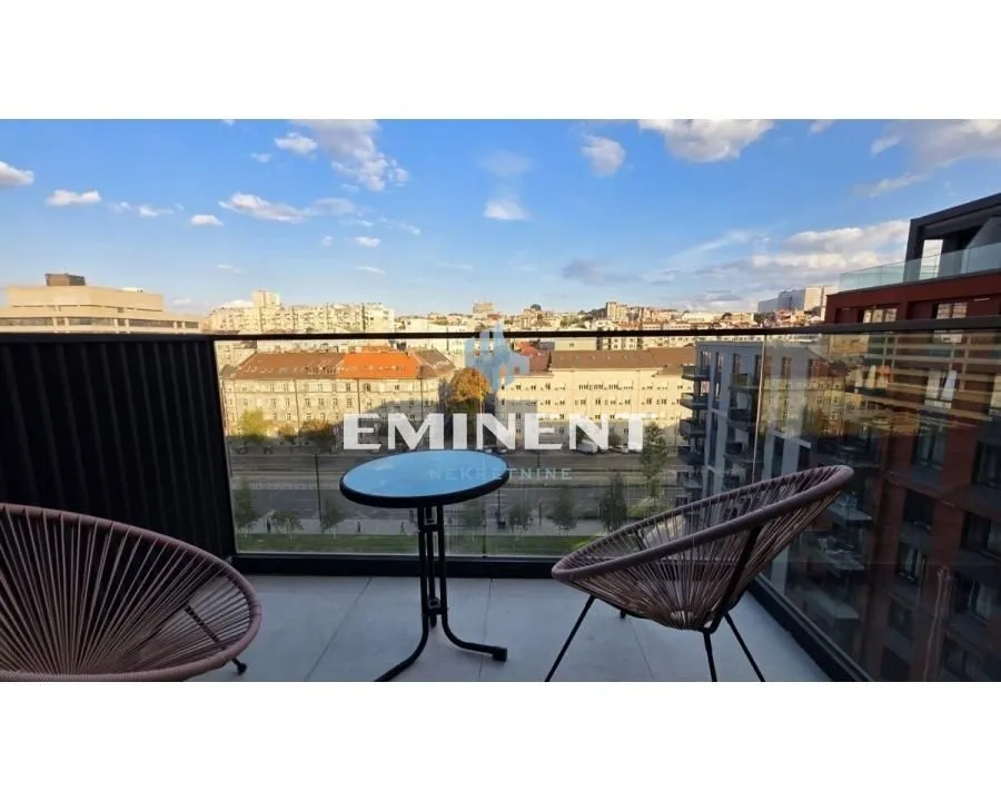 Namešten balkon sa stolom, stolicama i pogledom na grad.
