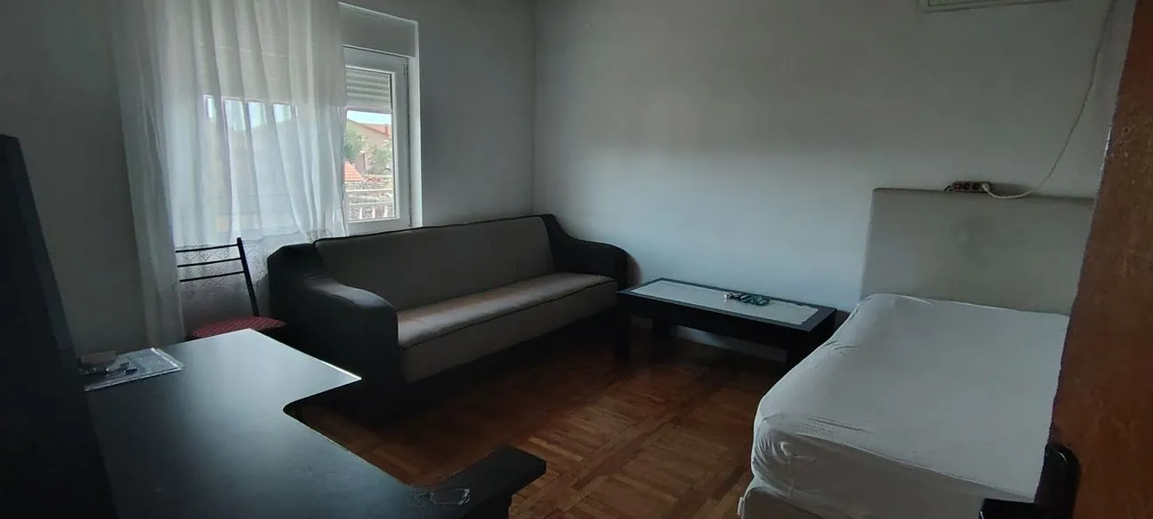 Furnished bedroom with a bed, sofa, and desk.