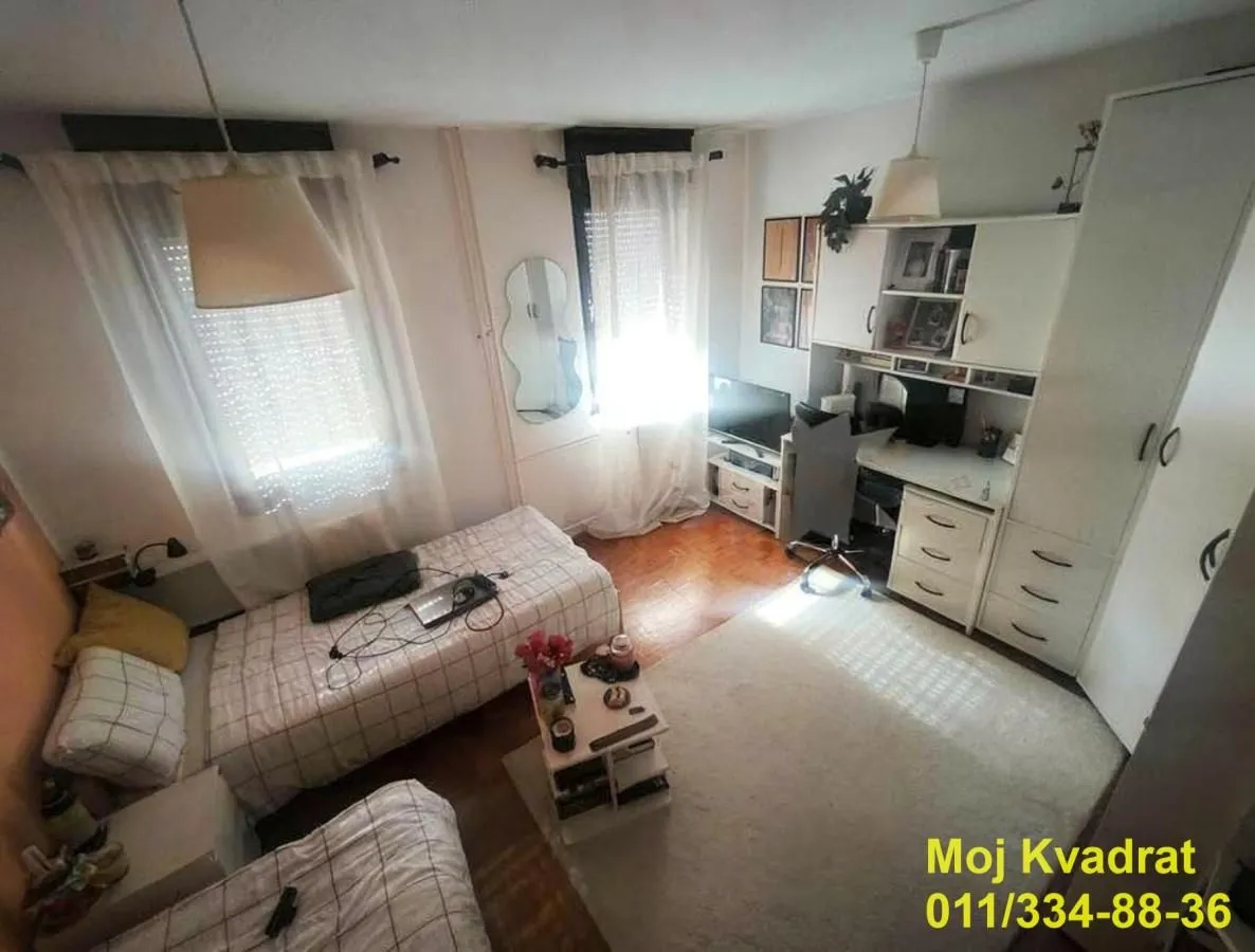 Dečja soba sa dva kreveta, radnim stolom i plakarom.
